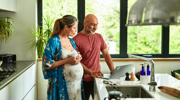 Couple expecting child review information on a computer