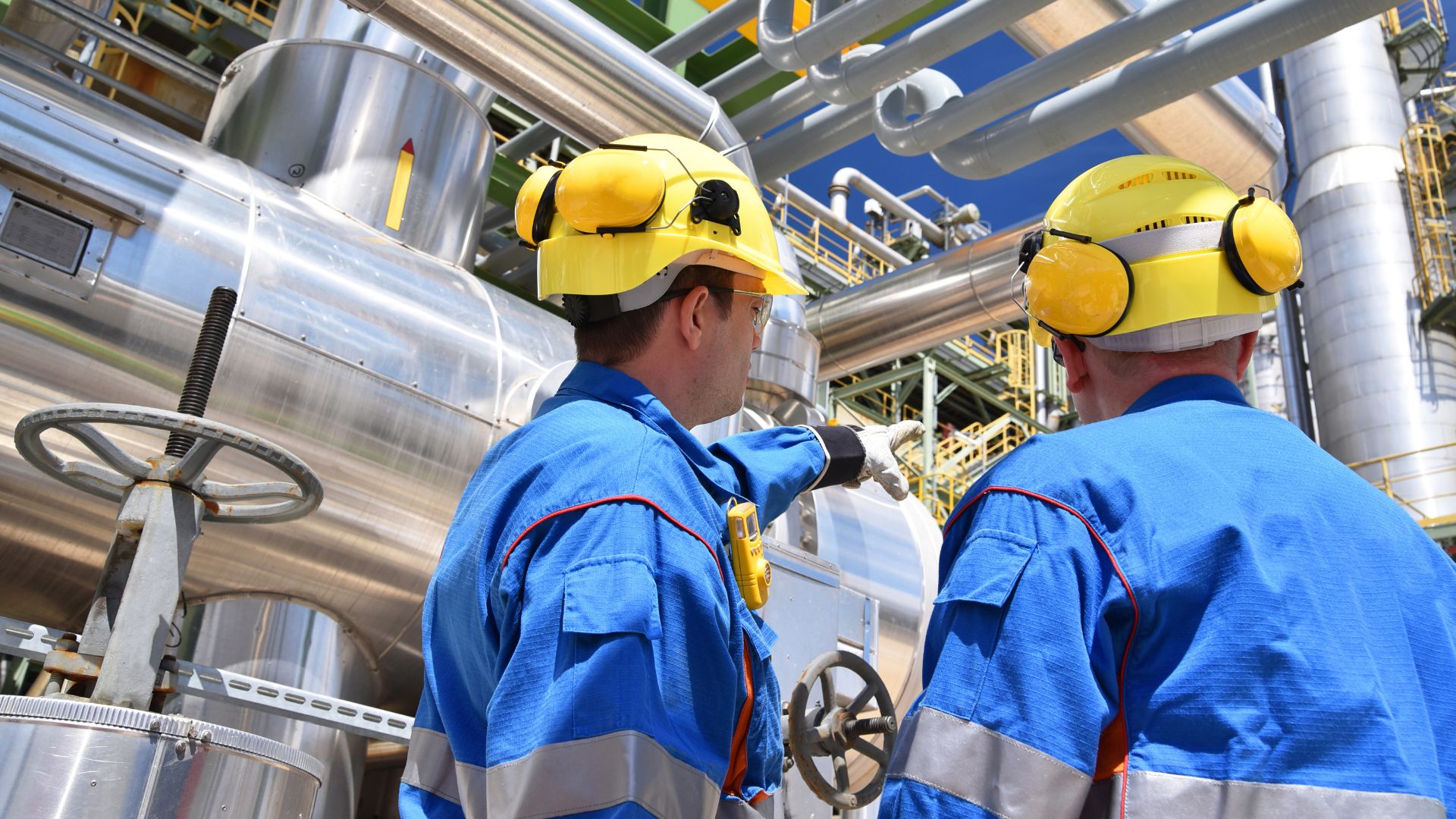 Two workers in oil and gas plant looking at equipment