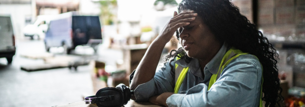 Stressed warehouse worker with her hands to her forehead.
