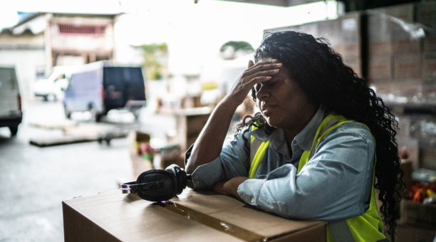 Stressed warehouse worker with her hands to her forehead.
