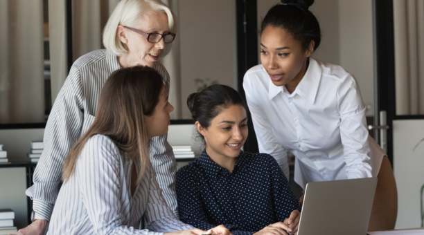 Multigenerational female employees working in a conference room together. 