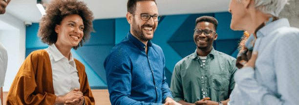 New hire shaking hands and meeting smiling coworkers.