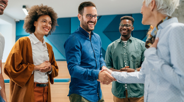 New hire shaking hands and meeting smiling coworkers.