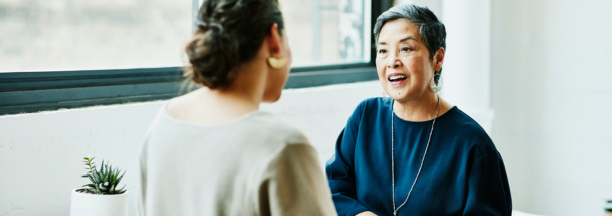 Benefits administrator meeting with an employee as they face each other.
