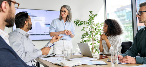 Female leader talking to employees in a conference room. 