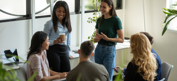 Young adult employees talking and laughing in a conference room. 