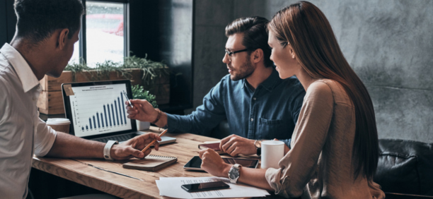 Three coworkers working together while looking at a laptop. 