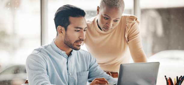Two employees looking at a laptop together at work. 