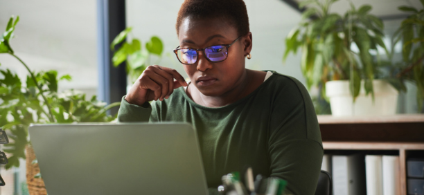 Female employee with glasses looking at laptop.