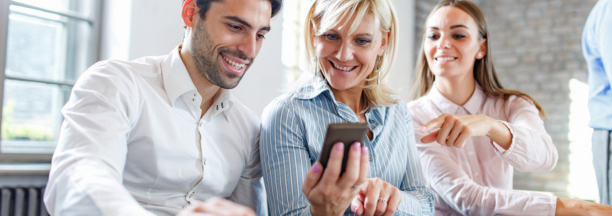 three employees looking at smartphone and smiling
