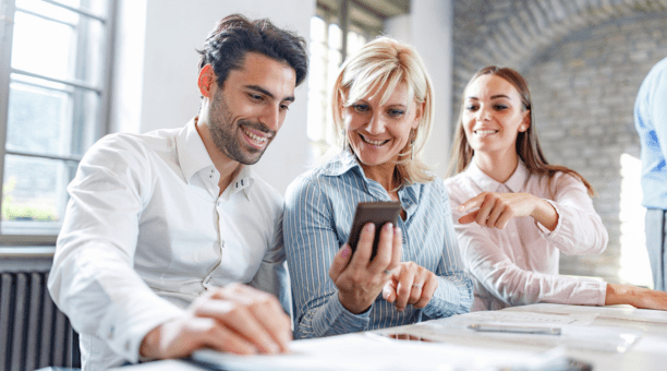 three employees looking at smartphone and smiling