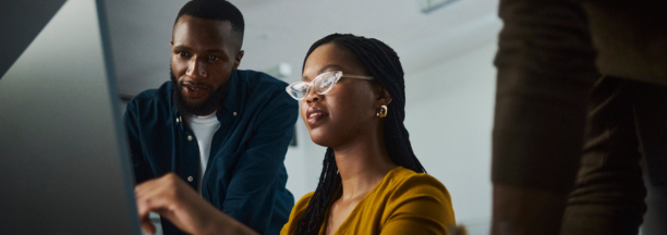 Three employees looking at a laptop.