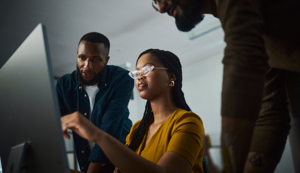 Three employees looking at a laptop.