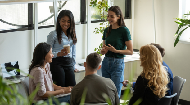 Young adult employees talking and laughing in a conference room.